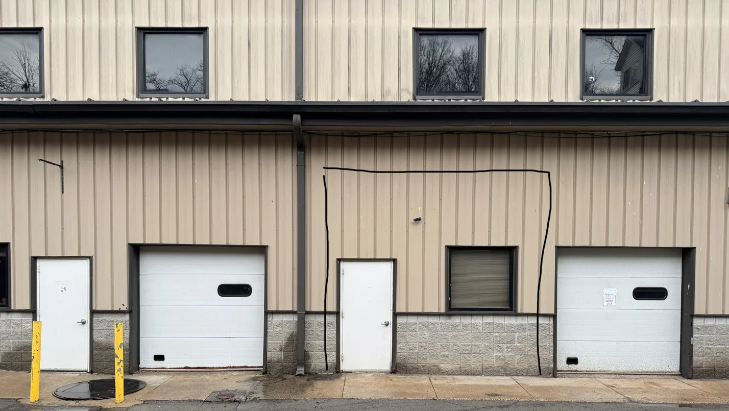 The same elevation before reinvestment, with tan siding and white service doors
